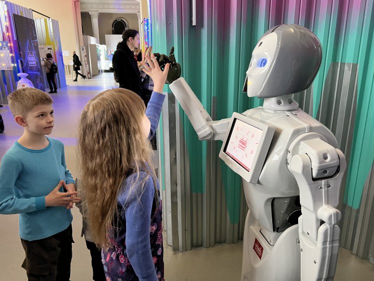 Робот Кики дает «пять» юной посетительнице на выставке «Робостанция»