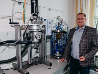 Старший научный сотрудник ИХХТ СО РАН Роман Владимирович Борисов на фоне стеклянного реактора и автоклава. Фото: Анастасия Тамаровская / ФИЦ КНЦ СО РАН
