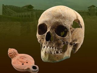 На этом изображении изображен череп восточноафриканца плюс масляная лампа с орлом легионера, с которой он был похоронен.
