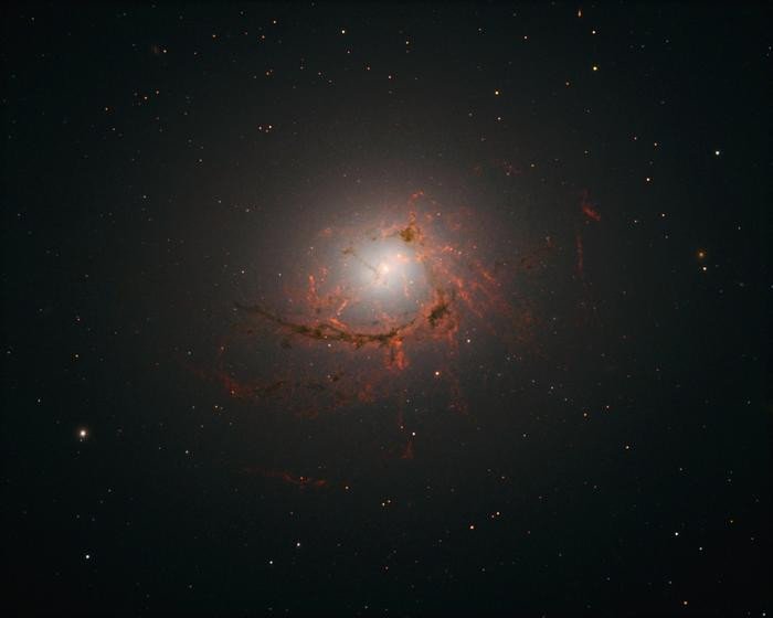 Снимок эллиптической галактики NGC4696, расположенной в центре скопления Центавр, сделанный космическим телескопом «Хаббл». На этом снимке видны пылевые нити, окружающие центр галактики. Фото: NASA, ESA/Hubble, A. Fabian