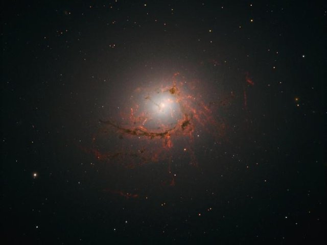 Снимок эллиптической галактики NGC4696, расположенной в центре скопления Центавр, сделанный космическим телескопом «Хаббл». На этом снимке видны пылевые нити, окружающие центр галактики. Фото: NASA, ESA/Hubble, A. Fabian