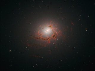 Снимок эллиптической галактики NGC4696, расположенной в центре скопления Центавр, сделанный космическим телескопом «Хаббл». На этом снимке видны пылевые нити, окружающие центр галактики. Фото: NASA, ESA/Hubble, A. Fabian